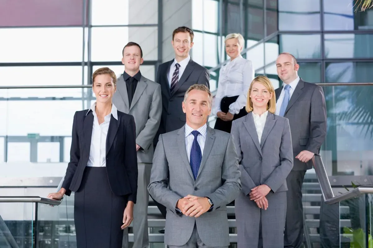 Team of business professionals in suits standing together on a modern office staircase